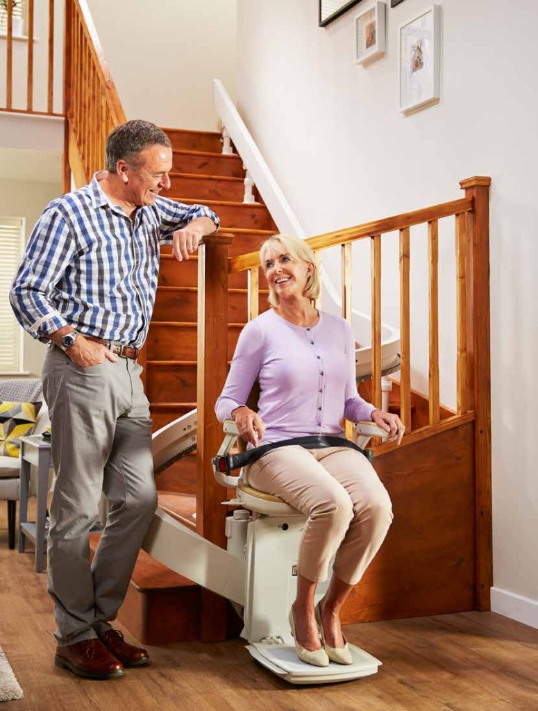 Couple senior : monte-escalier en pied d’escalier bois, ambiance intérieure lumineuse et chaleureuse